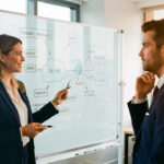 Une consultante en informatique présente une architecture cloud sécurisée à un dirigeant, dans un échange professionnel axé sur la confiance et la valeur à long terme.